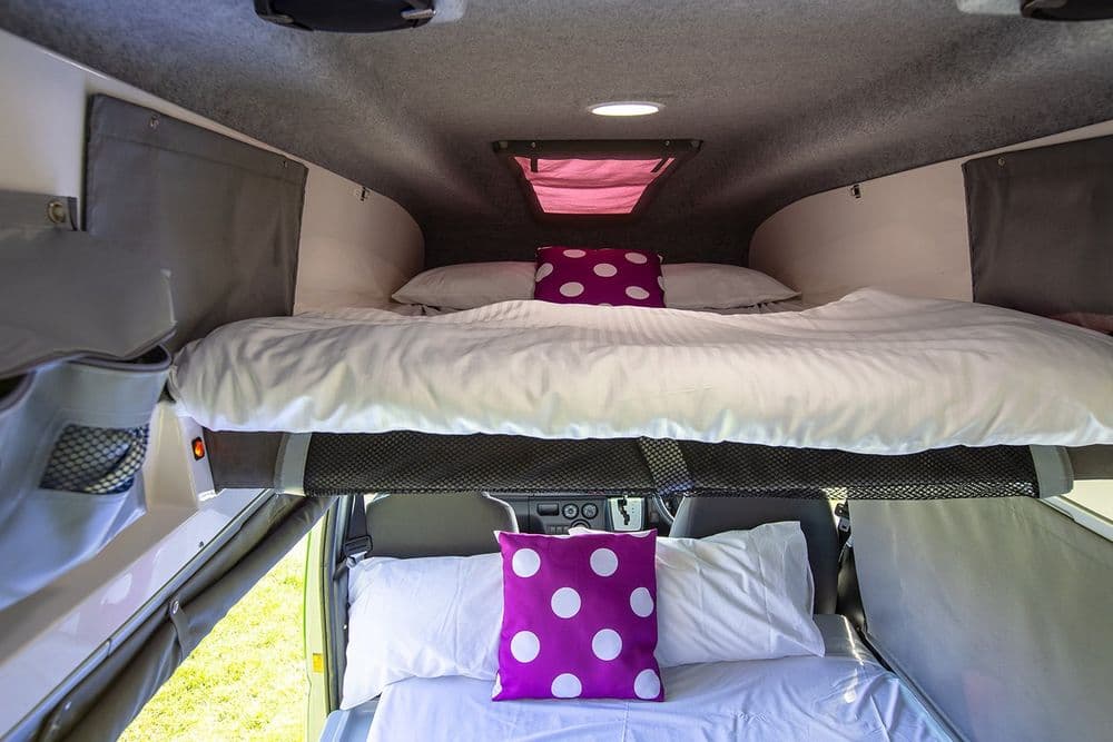 Both campervan beds made up, one in the raised roof pod above and one across the floor below