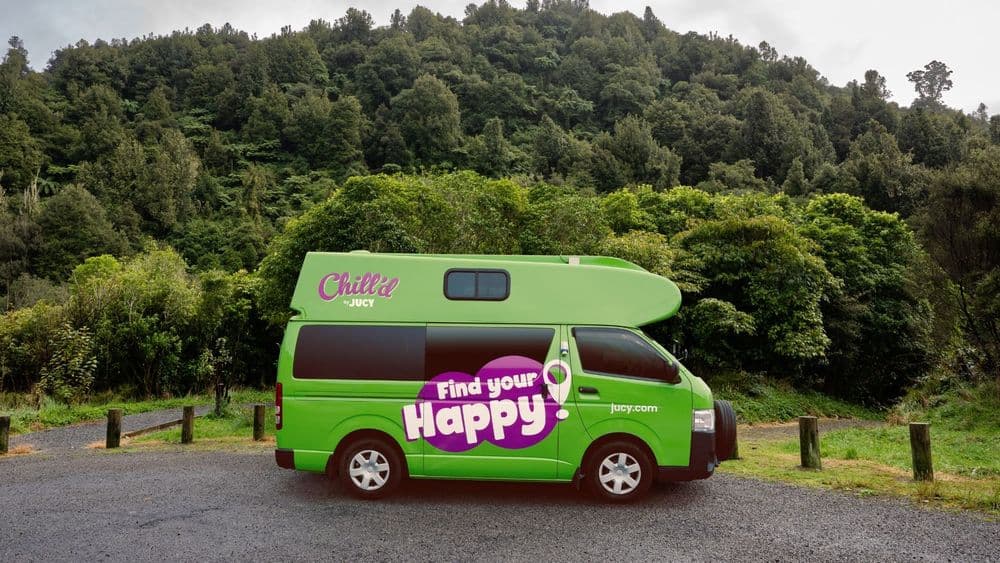 Green high-roof Toyota HiAce campervan in Find Your Happy livery with a small Chill'd badge on the raised roof pod